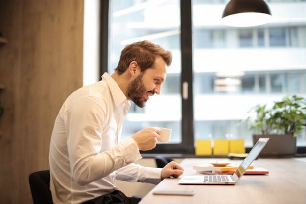 A man drinking coffee and using his laptop